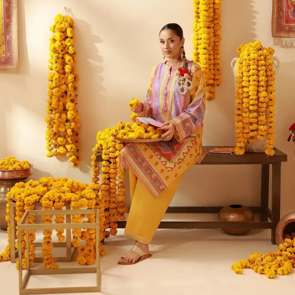 Woman in traditional attire sitting amidst yellow floral decorations in a decorated room.
