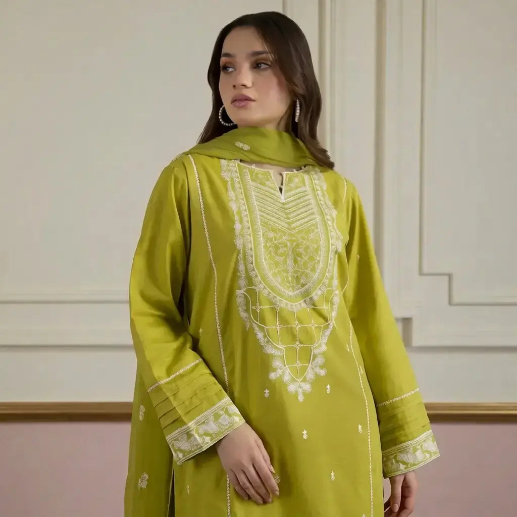 Woman wearing a green embroidered traditional outfit against a neutral background